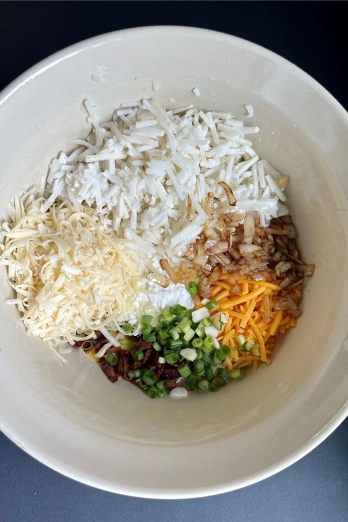 adding-the-hashbrowns-and-cheese Breakfast Casserole ingredients in a bowl.