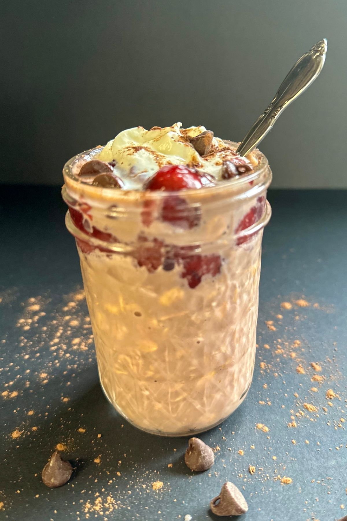 Black Forest Overnight Oats with whipped cream and a spoon.