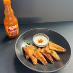 Bowl of Buffalo Chicken Dipper Bites and a bottle of buffalo sauce.