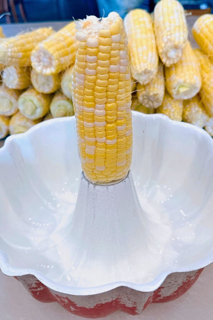 Cutting corn off the cob into bundt pan.