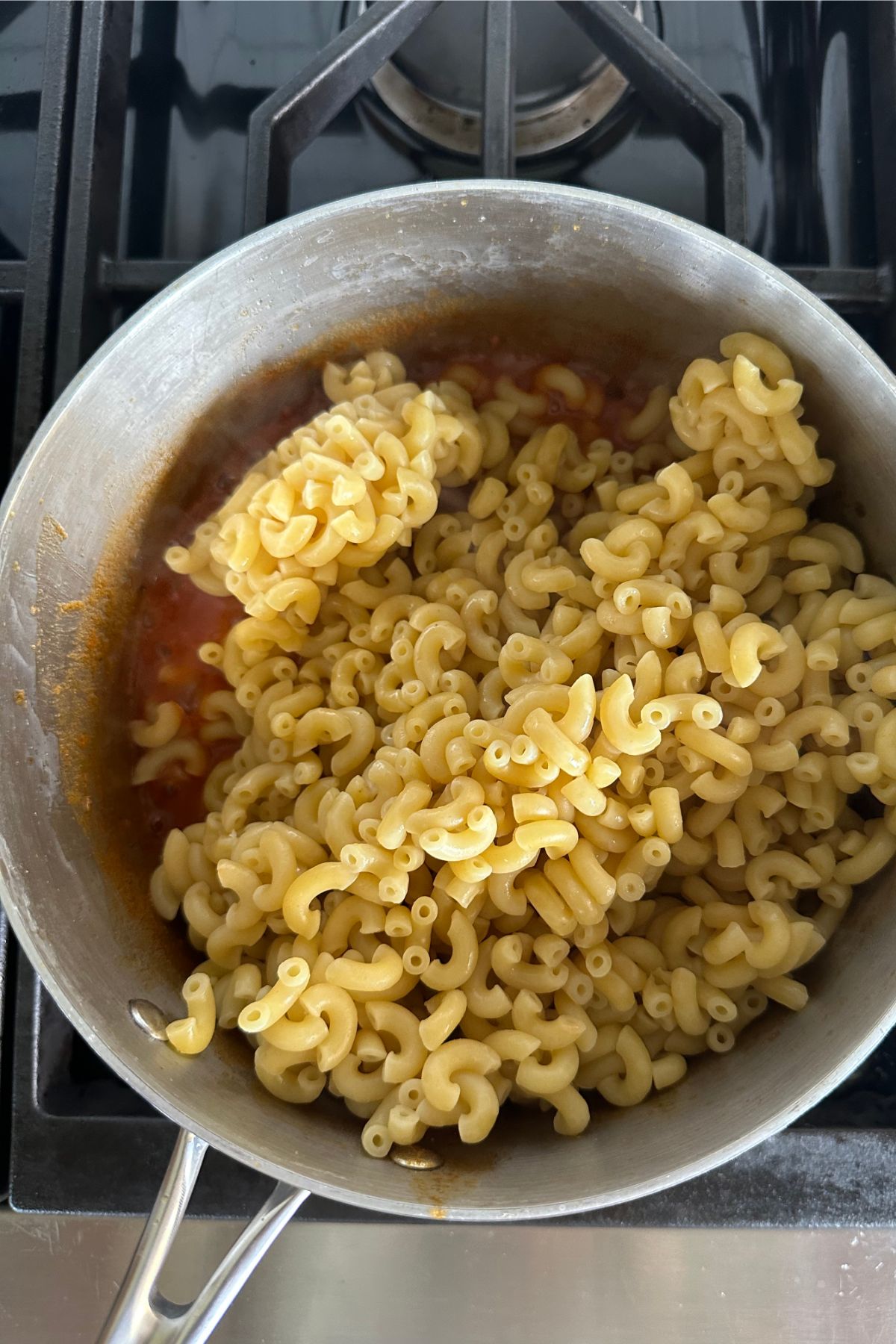Adding macaroni to pot of ingredients.