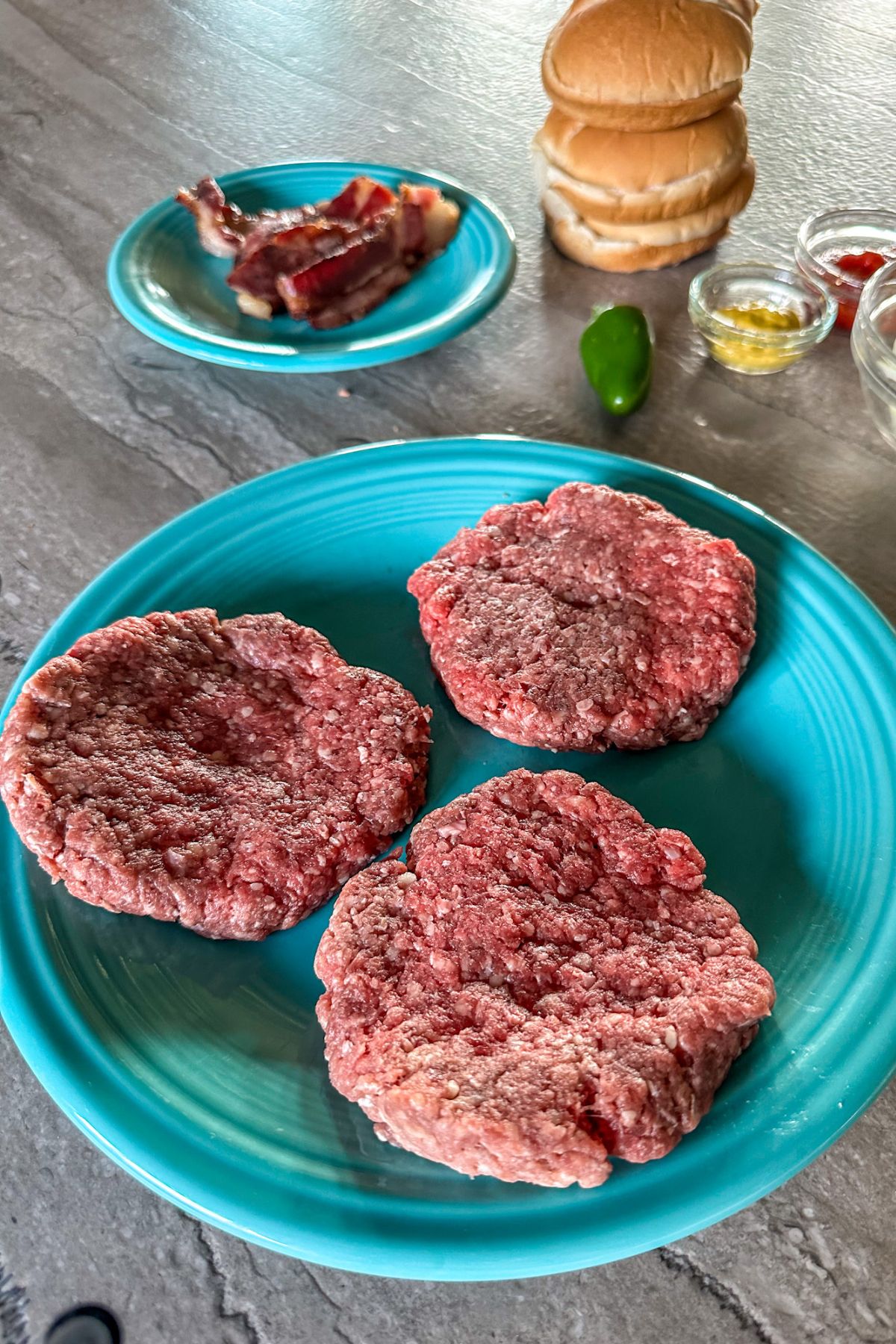 Raw ground beef patties on a plate.