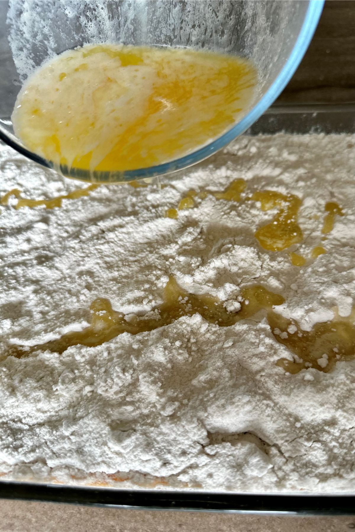 Drizzling butter on cake mix.