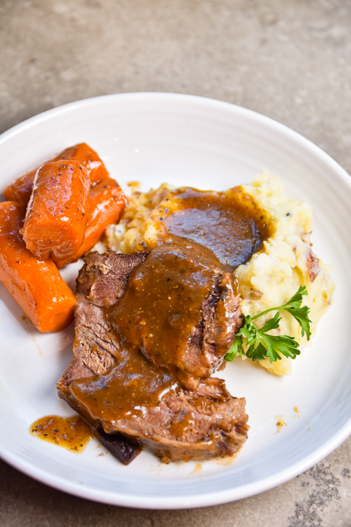 pot-roast-gravy Plate of pot roast with mashed potatoes and carrots.