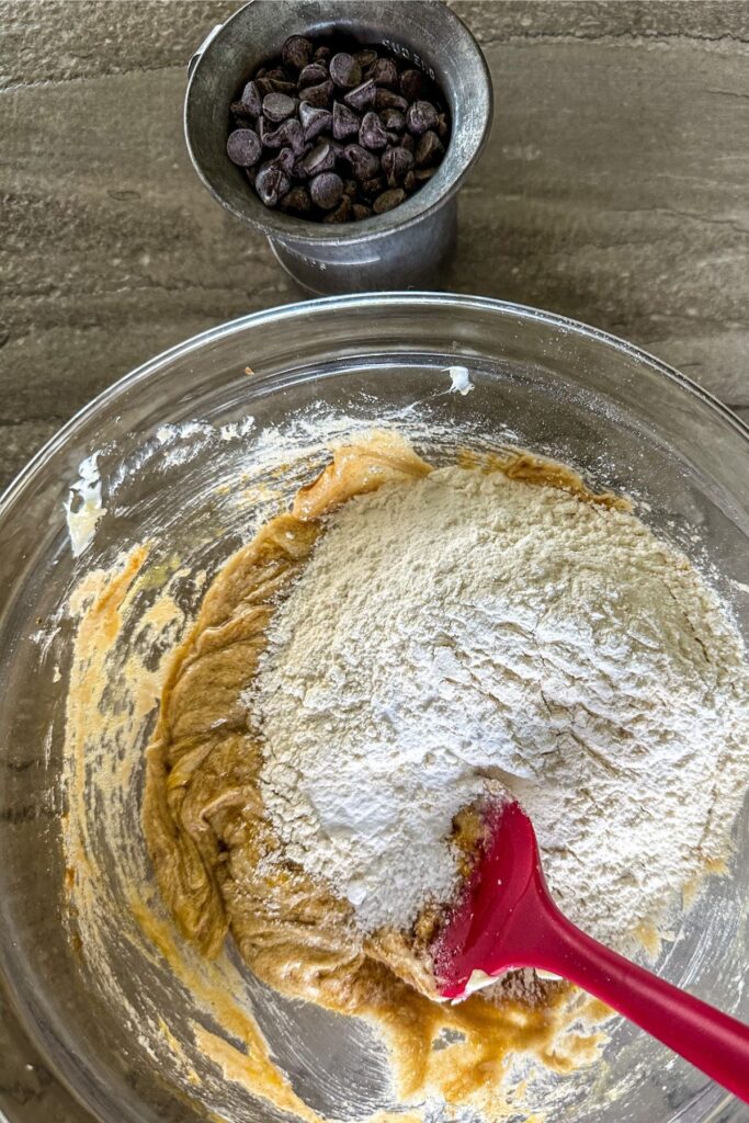 Adding flour to cookie mixture in a bowl. 