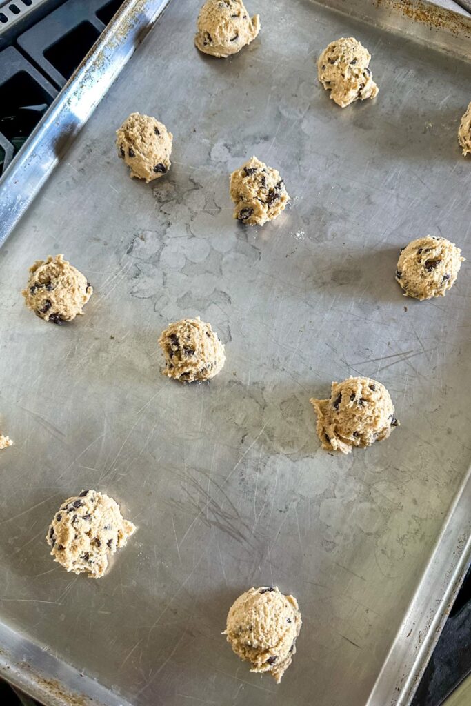 Scoops of Bacon Grease Chocolate Chip Cookie dough on a baking sheet.