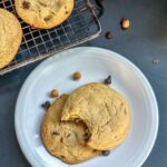 Two Caramel Chocolate Chip Cookies on a plate with a bite taken out of one.