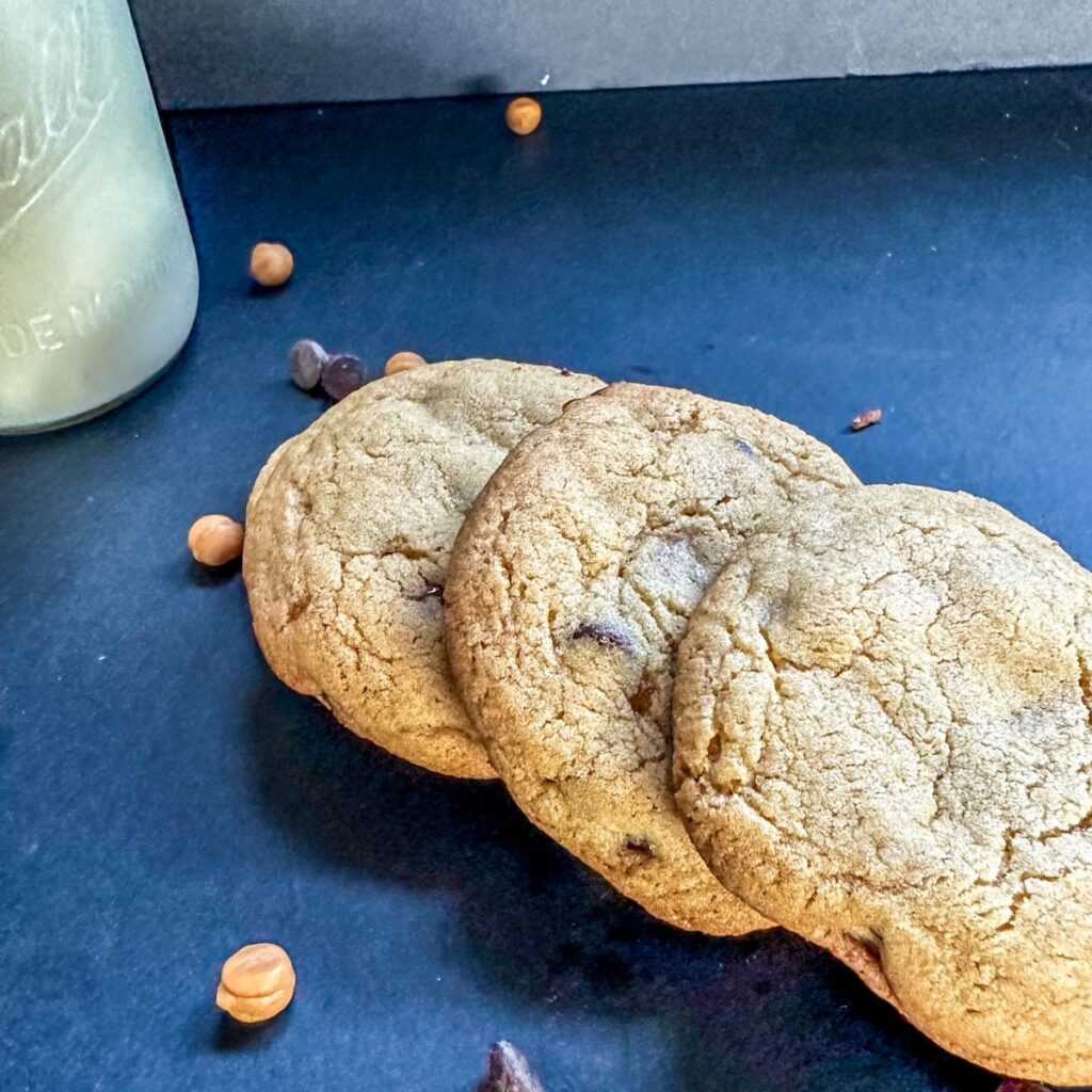 Row of Caramel Chocolate Chip Cookies with a glass of milk. 