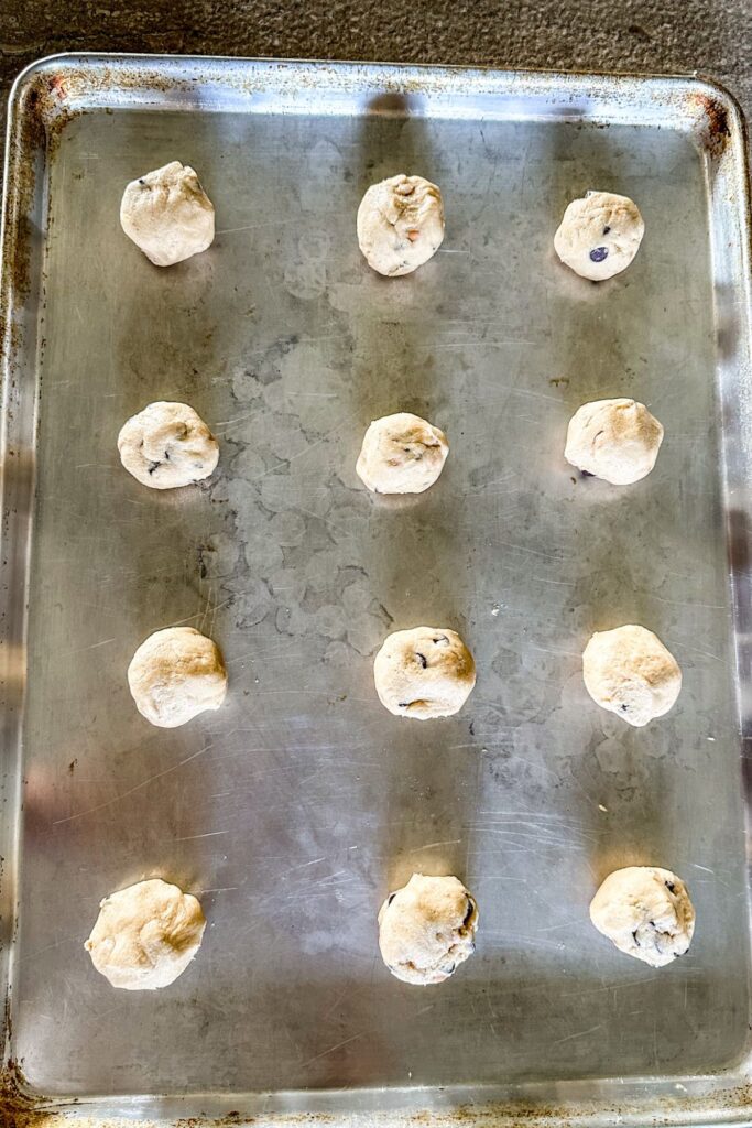 Scoops of Caramel Chocolate Chip Cookie dough on a baking sheet.