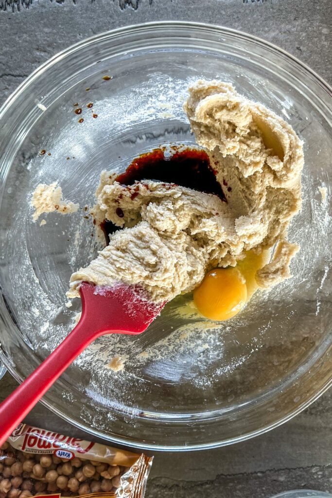 Adding egg and vanilla into cookie dough batter. 