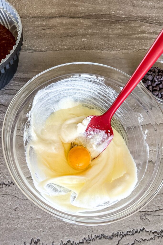 Stirring egg into cream cheese cake filling.