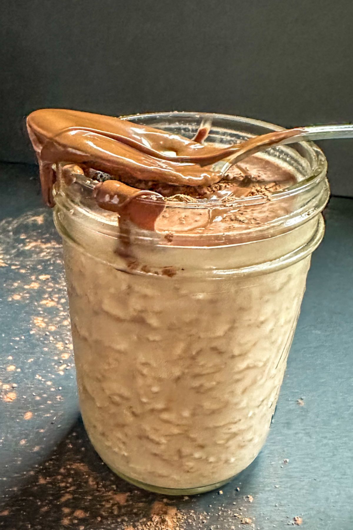 Nutella Overnight Oats in a jar with a Nutella covered spoon.
