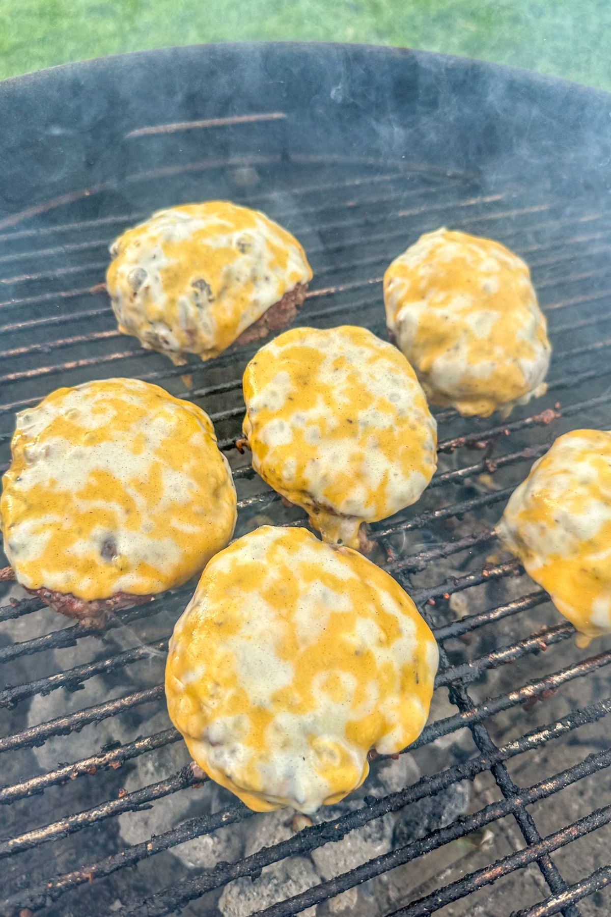 Rodeo Burger patties on the grill with melted cheese.