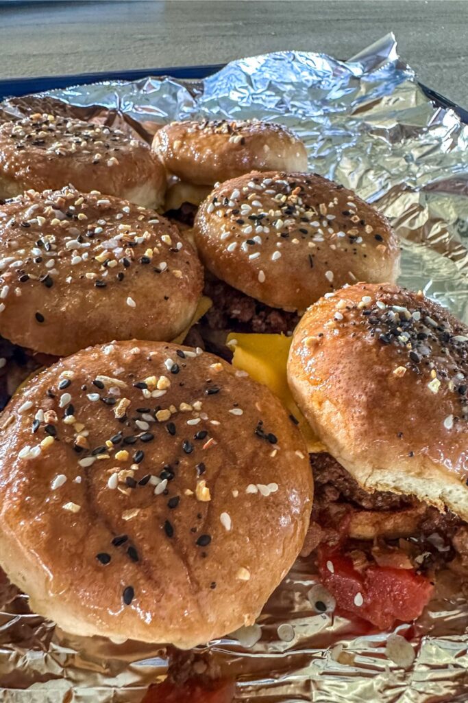 Sheet of Sliders topped with butter, brown sugar, and Everything but the Bagel Seasoning.