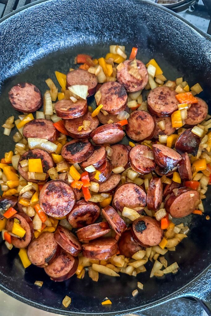 Onions, peppers, and kielbasa in a skillet.