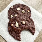 Two Chocolate Chip Cookies with White Chips on a napkin.