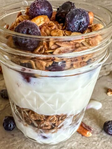 A jar of Maple Pecan Granola with berries.