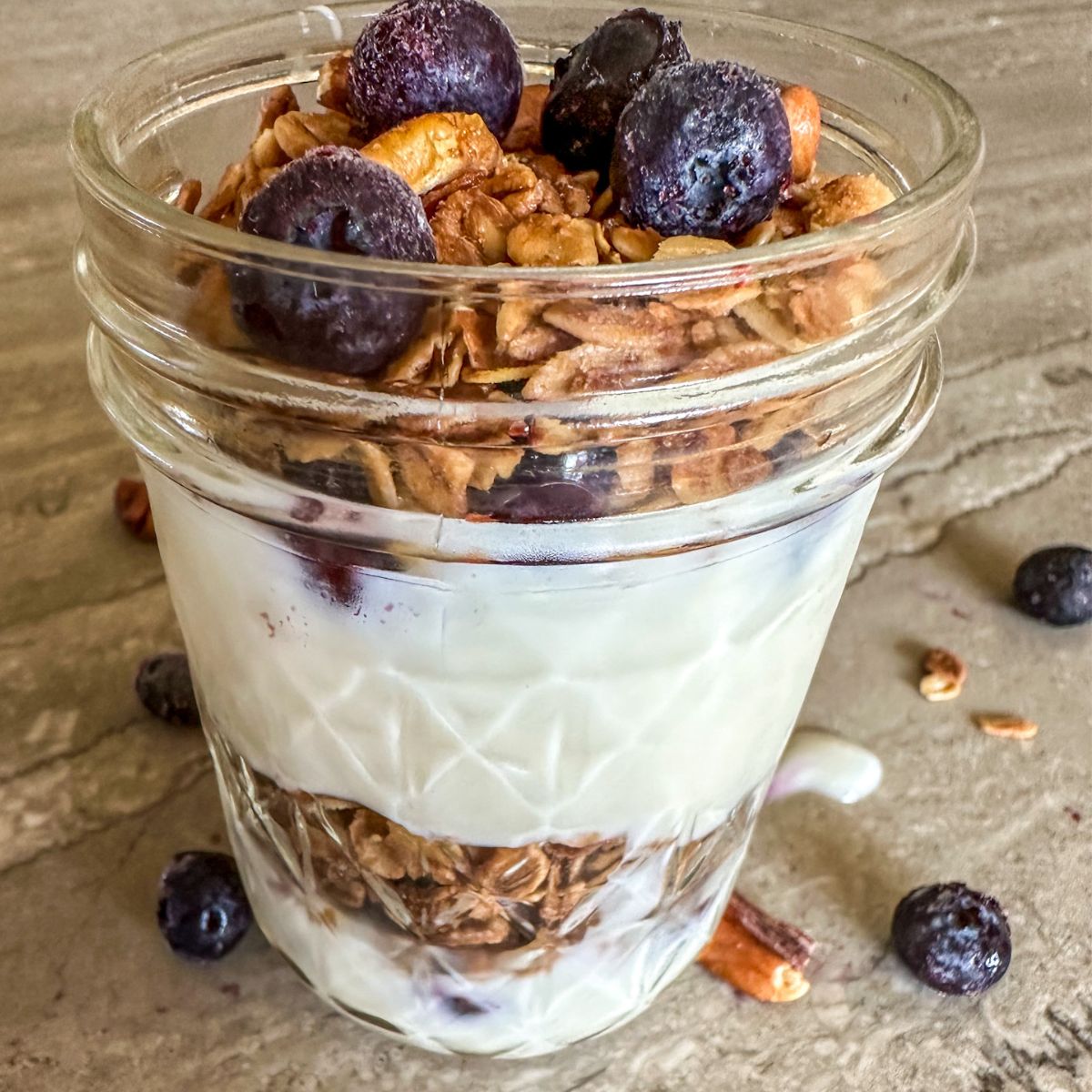 A jar of Maple Pecan Granola with berries. 