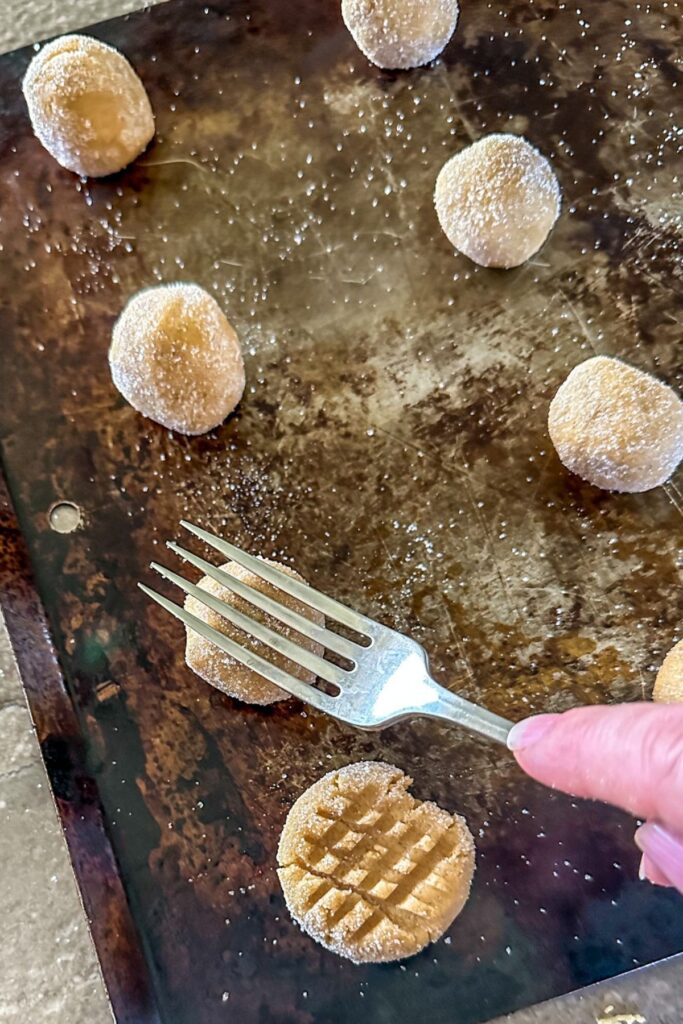 Using a fork to make a crisscross pattern on Peanut Butter Cookie dough.