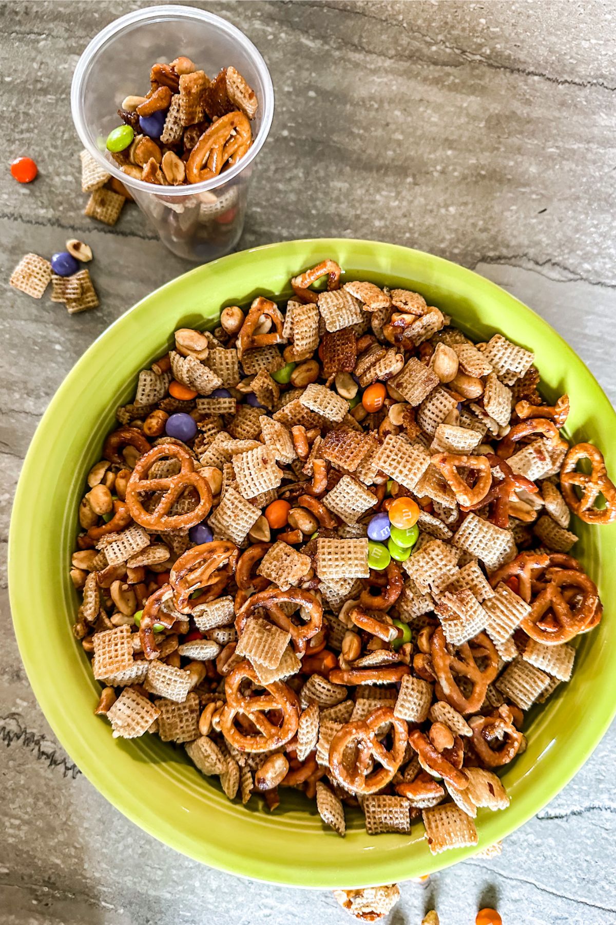 A bowl and small cup full of Snack Mix.