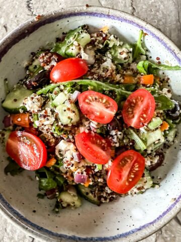 arugula and quinoa salad being served in a white dish.