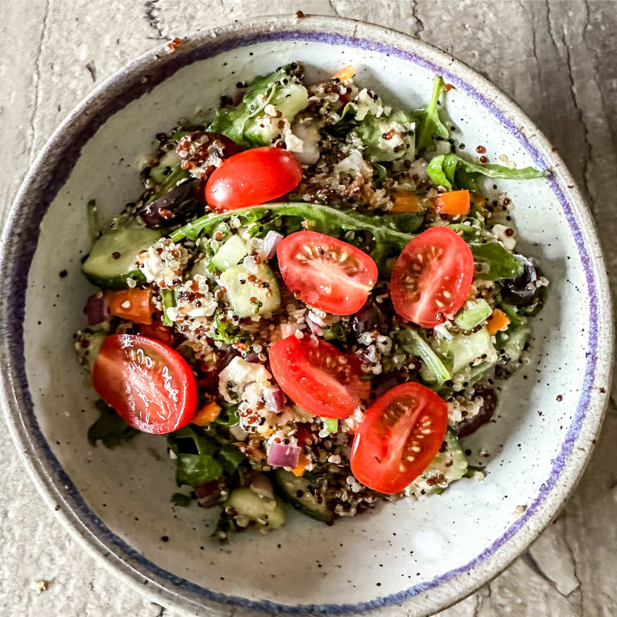 arugula and quinoa salad being served in a white dish.