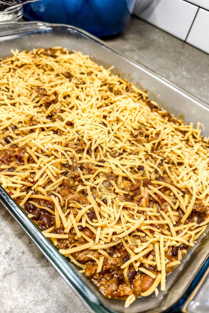 adding cheese to the chili base.