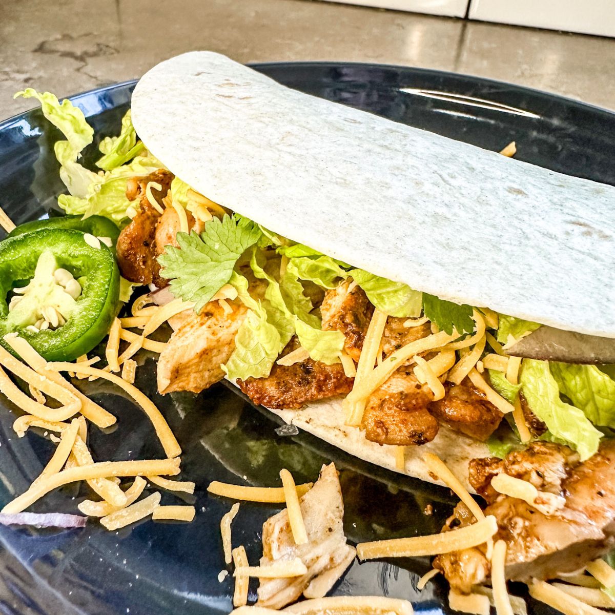 chicken taco being served with jalapeno.