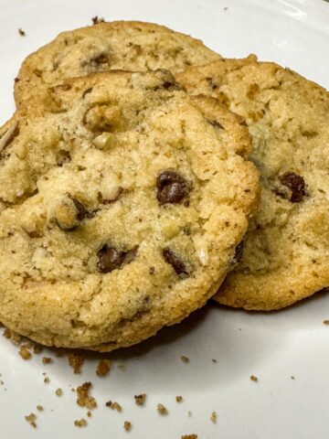 chocolate chip pecan cookies are being served on a white plate.