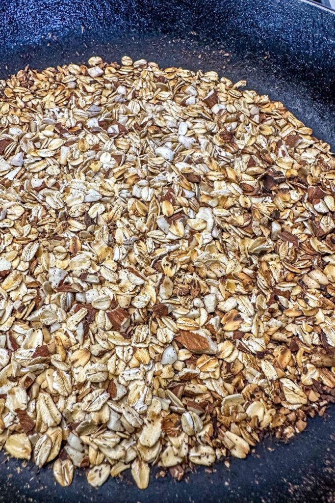 toasting oats and almonds in a pan.