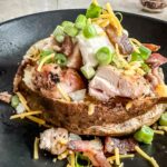 chicken bacon ranch baked potatoes on a black plate.