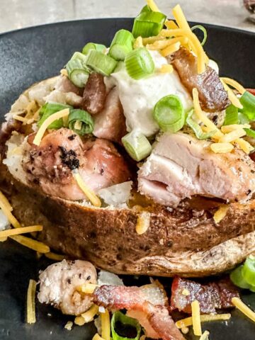 chicken bacon ranch baked potatoes on a black plate.