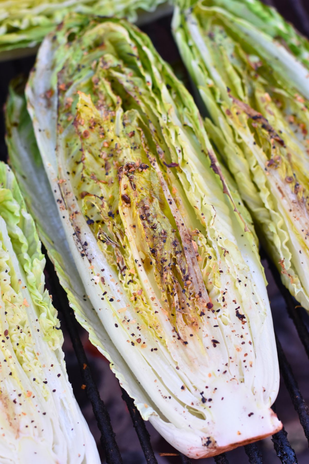 cut-the-romaine-lettuce-in-half-and-season Roasted romaine lettuce covered in seasoning on the grill.