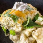 creamy chicken and spinach enchilada casserole topped with sour cream.