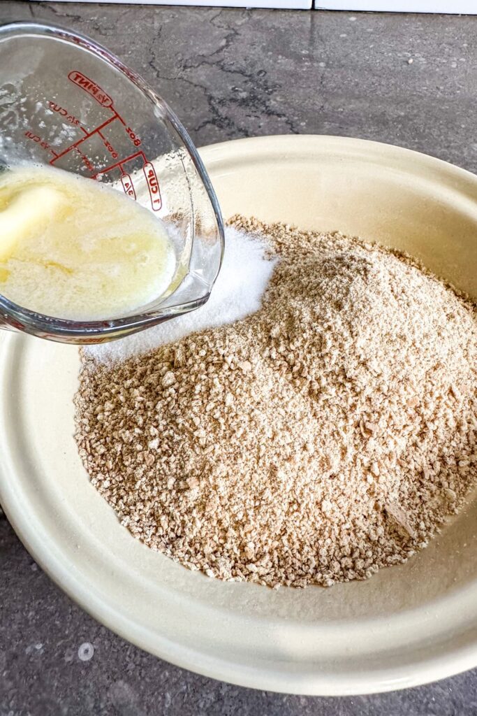 pouring-butter-and-sugar-into-the-crumbled-graham-crackers Adding butter and sugar to the graham cracker for the chocolate cream pie crust.