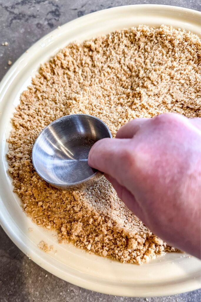 shaping-the-graham-cracker-to-the-pie-pan firmly pressing the crumbs across the bottom and up the sides for the chocolate cream pie.