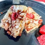 white chocolate and raspberry blondies served on a gray plate.