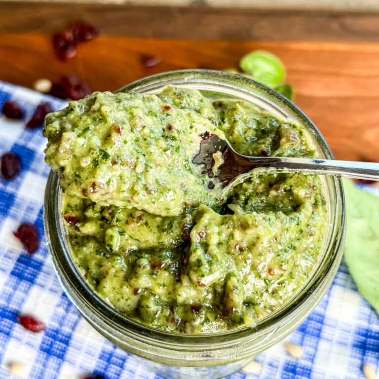 Scooping pesto out of a mason jar with a spoon.