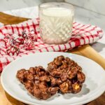 Peanut Clusters served on a white plate with a glass of cold milk.