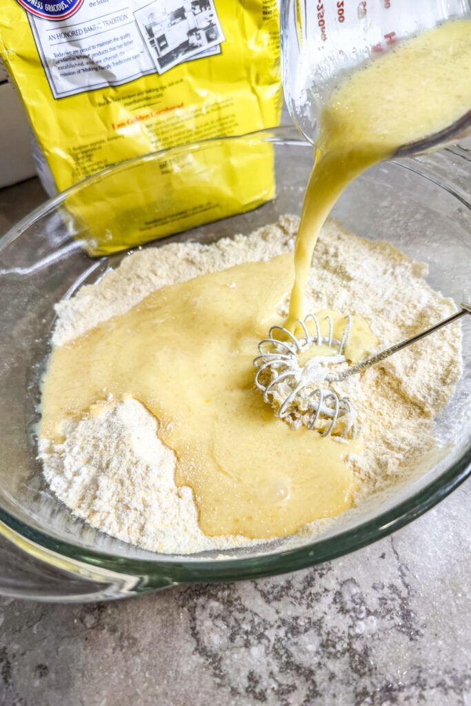 adding the wet ingredients into the dry ingredients for cornbread sticks.