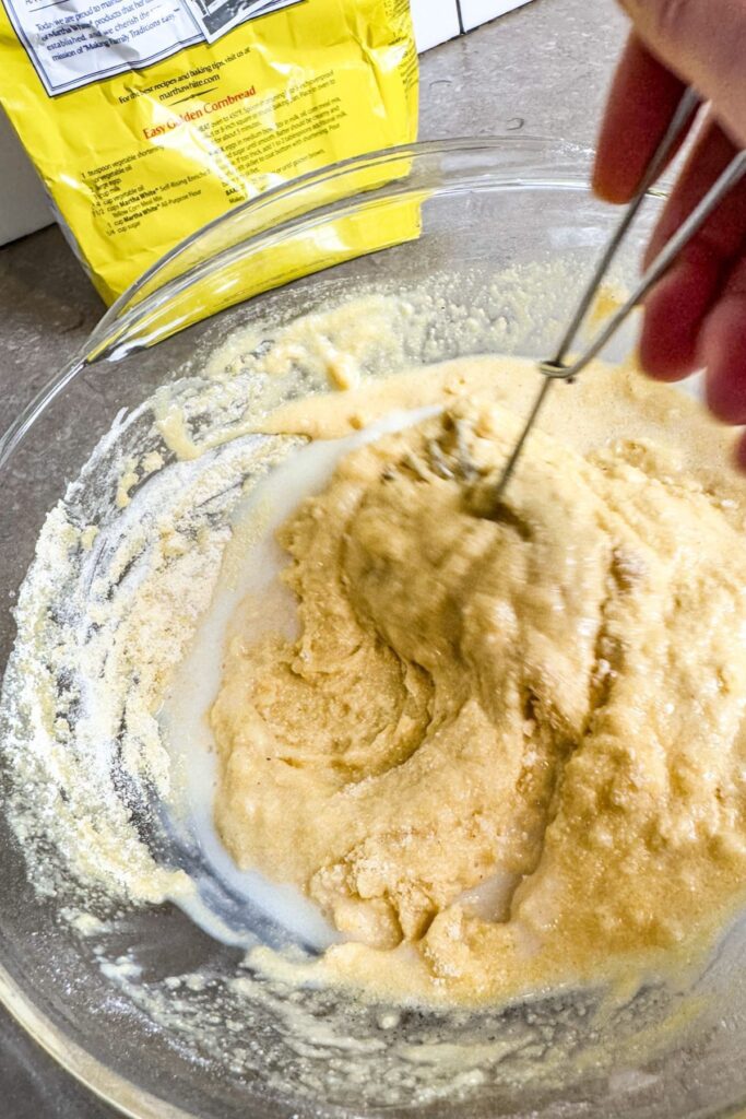 Mixing the wet ingredients with the dry ingredients for homemade cornbread sticks.
