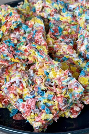 Fruity pebbles cereal bars stacked on a black plate.