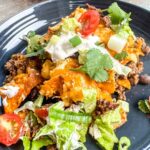 Supreme walking taco casserole served on grey plate.