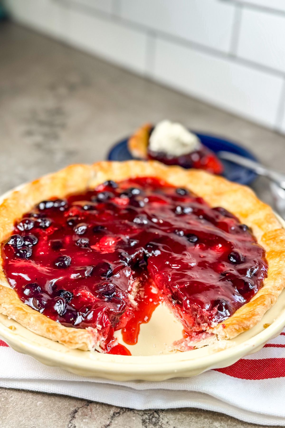A slice cut out of a beautiful blueberry strawberry pie is then served.