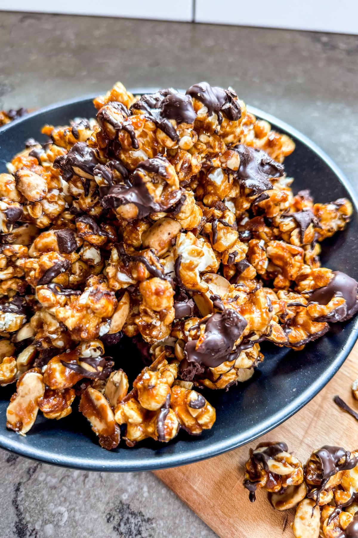 Serving chocolate drizzled caramel corn in a black bowl.