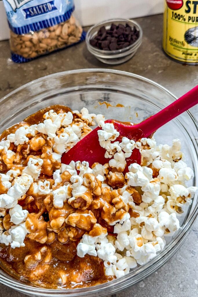 Mix the caramel into the popcorn to create a mixture to make chocolate drizzled caramel corn.