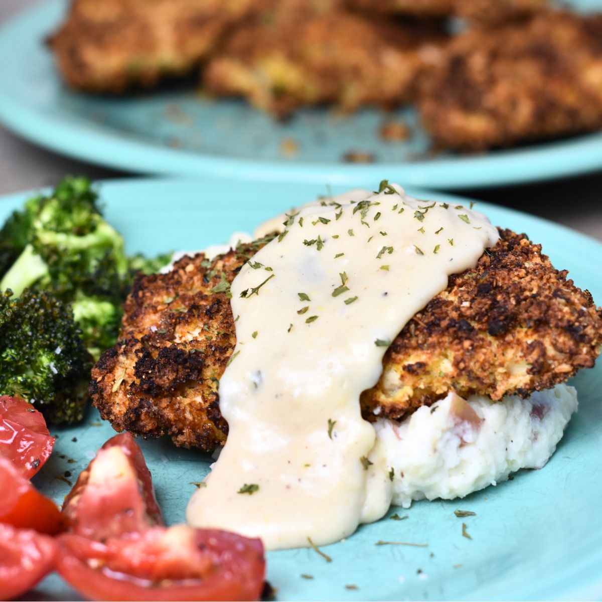 Parmesan-Crusted-Chicken-served-on-a-bed-of-mashed-potatoes Parmesan Crusted Chicken served with a ranch gravy.
