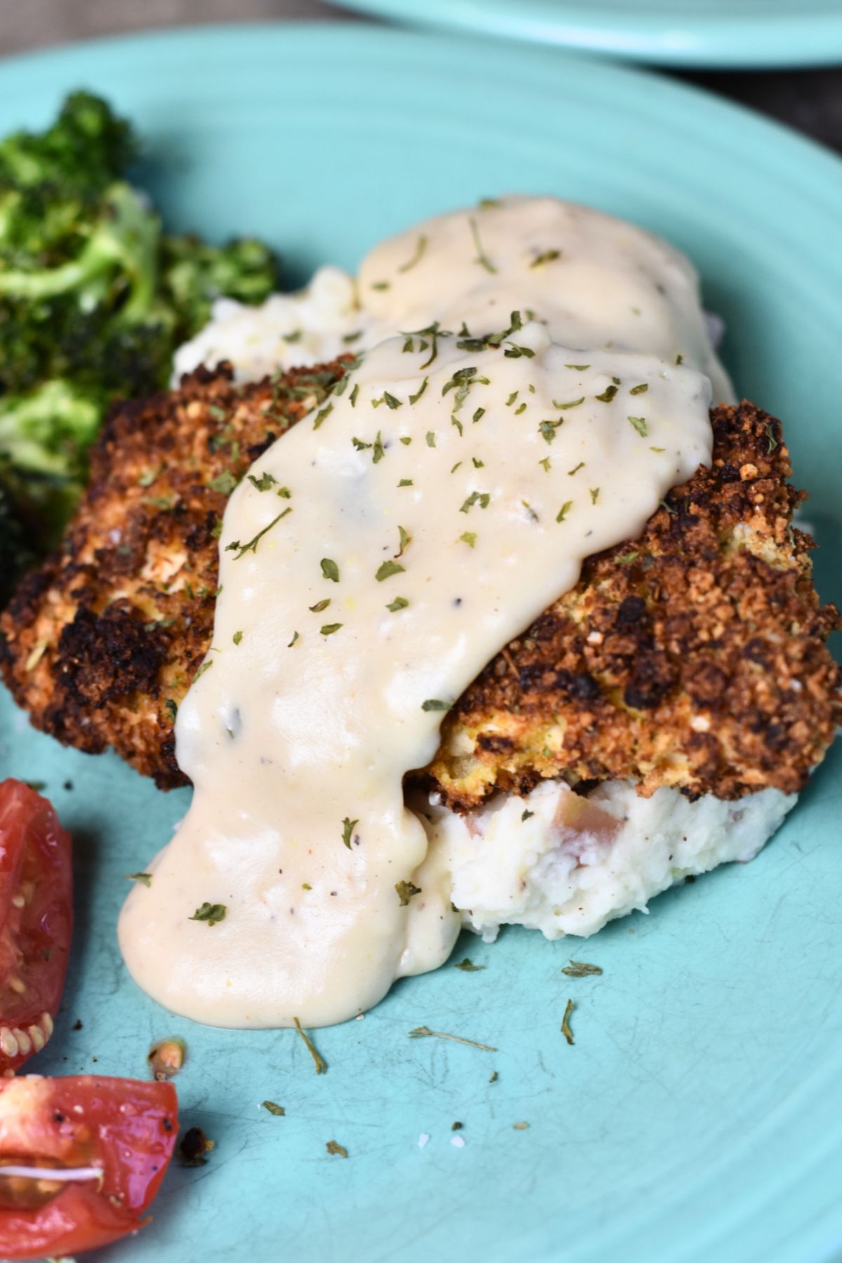 Crispy parmesan ranch crusted chicken served with broccoli and sliced tomatoes.