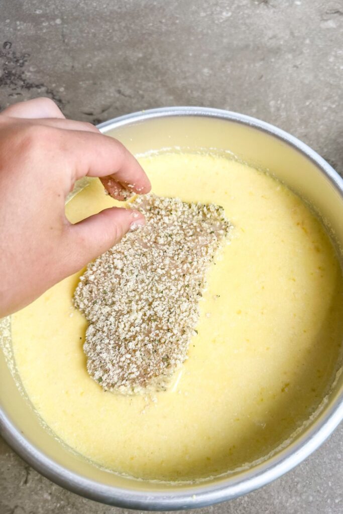 Adding my parmesan crusted chicken back into the egg mixture for a crispy crust.