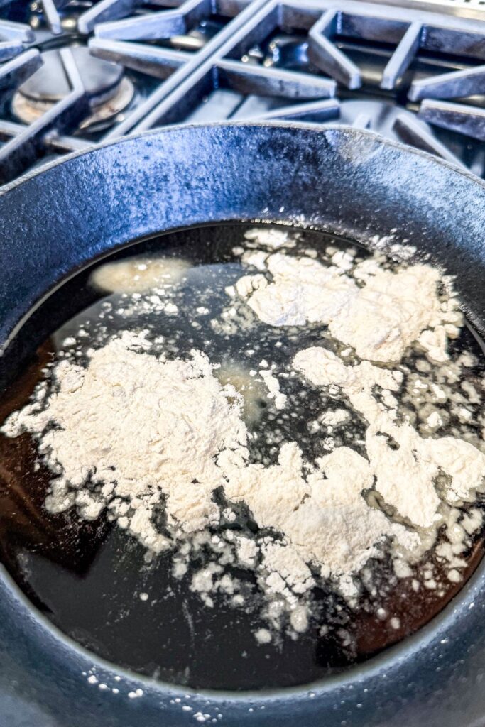 Adding flour to hot bacon grease for chicken gravy.